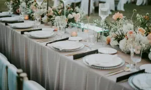 Elegancko nakryty stół weselny z kwiatami i świecami. Taka tania dekoracja sali weselnej zachwyci gości.