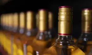 Rząd butelek z alkoholem, każda z złotą zakrętką. Zastanawiasz się, jednostka alkoholu ile to?