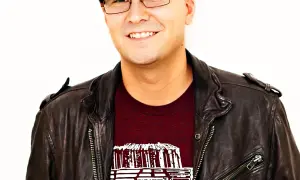 A smiling man in a leather jacket and cap, possibly inspired by the creative spirit behind Luke Laird songs.