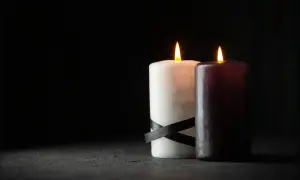 Dwie płonące świece, biała z czarną wstążką i ciemna, symbolizują patologiczną żałobę, która nie ustępuje.