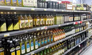 Scaffali di un supermercato pieni di bottiglie di olio d'oliva. Quante olive per un litro di olio? La risposta è nella varietà di marche e formati.