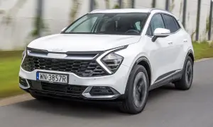 Biała Kia Sportage 1.6 benzyna w ruchu, z widocznym grillem i reflektorami.