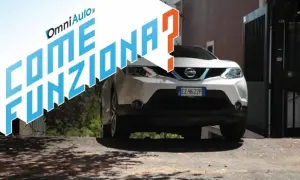 Nissan bianco su strada in salita, con testo "Come funziona?". Spiegazione del sistema hill holder.