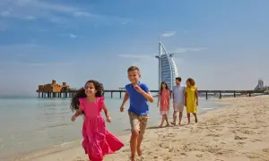 Rodzina bawi się na plaży w Dubaju, z hotelem Burdż al-Arab w tle. Czy w Dubaju jest bezpiecznie? Tak, to idealne miejsce na rodzinne wakacje.
