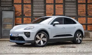 Biały Porsche Macan Electric na bruku przed ceglanym budynkiem. Sprawdź aktualną porsche macan cena.