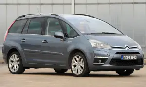 Szary Citroen C4 Grand Picasso 2.0 HDI z kierowcą za kierownicą, zaparkowany przed budynkiem.