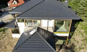 Nowy, ciemny dach na domu w budowie. Zastanawiasz się, ile kosztuje wymiana dachu? Sprawdź ceny!