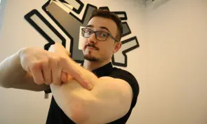 Mężczyzna w okularach wskazuje palcem na zewnętrzną stronę łokcia.