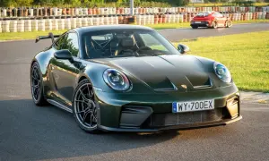 Zielony Porsche 911 GT3 na torze wyścigowym, z innym czerwonym samochodem w tle.