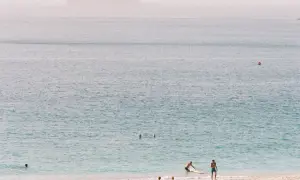 Ludzie odpoczywają na plaży, w tle widać ocean i wyspy. Zastanawiasz się, ile trwa lot na Wyspy Zielonego Przylądka?