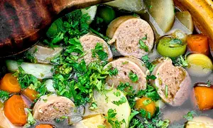 En närbild på en mustig korvgryta med potatis, morötter och purjolök, toppad med färsk persilja. Ett perfekt korvgryta recept för kalla dagar.