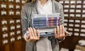 Kobieta trzyma stos książek i broszur, gotowych do wysyłki dzięki usłudze print on demand.
