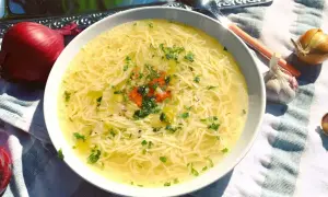 Aromaticzny, złocisty, dobry rosół z makaronem i natką pietruszki, obok cebula i czosnek.