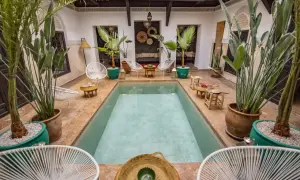 Ein Riad in Marokko: Ein Innenhof mit Pool, Pflanzen und Sitzgelegenheiten, typisch für marokkanische Architektur.