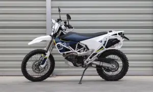 Biały lekki motocykl turystyczny z niebieskim siedzeniem i bagażnikiem, gotowy na przygodę.