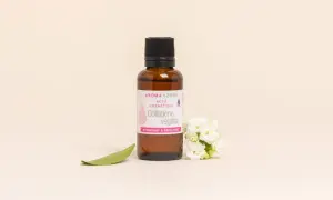 Flacon de collagène végétal Aroma-Zone, aux bienfaits hydratants et repulpants, entouré de fleurs blanches et d'une feuille verte.