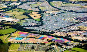 Aerial view of a vibrant Glastonbury map, showcasing a sprawling landscape of colorful tents and parked cars, a testament to the festival's immense scale.