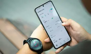 Ręka trzyma telefon Samsung z aplikacją Samsung Health, pokazującą kroki i aktywność. Zegarek na nadgarstku synchronizuje dane, pomagając jak znaleźć telefon Samsung.