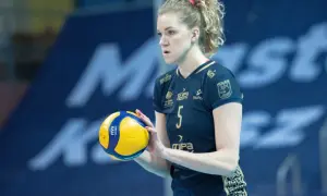 Agnieszka Korneluk, siatkarka z numerem 5, trzyma piłkę. Jej mąż pewnie kibicuje jej z trybun.