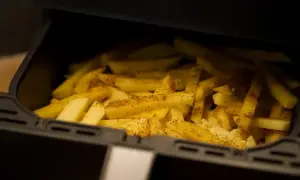 Frytki w koszu frytkownicy beztłuszczowej, przyprawione ziołami.