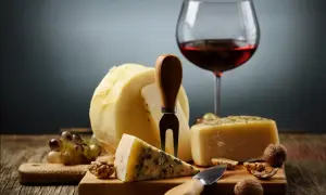 En härlig ost och vinprovning med olika ostar, vindruvor, nötter och ett glas rött vin.