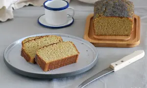 Rebanadas de bizcocho sin azucar con semillas de amapola, servidas en un plato gris junto a una taza y un cuchillo.
