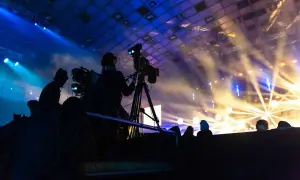 Operatorzy kamer w akcji podczas koncertu. W tle scena oświetlona reflektorami, tworząca magiczną atmosferę.