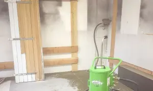 Préparation pour le décapage volet bois : une porte en bois est appuyée contre un mur, avec une machine de décapage à proximité.