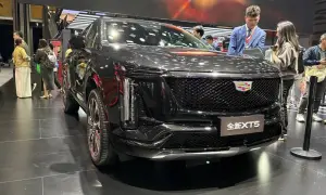 Elegancki, czarny Cadillac XT5 na wystawie. Ludzie oglądają nowy model, który przyciąga uwagę swoim designem.