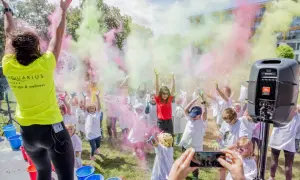 Kolorowy festiwal proszków w Kołobrzegu! Dzieci w białych koszulkach rzucają kolorowymi proszkami, tworząc radosną atmosferę. To świetne kołobrzeg atrakcje dla dzieci.