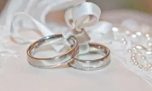 Anillos de oro blanco atados con cinta, uno con diamantes. El oro blanco se pone feo con el tiempo, pero el amor perdura.