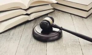 Młotek sędziowski i otwarte księgi na drewnianym stole. Dowiedz się, jak napisać apelację od wyroku o alimenty.