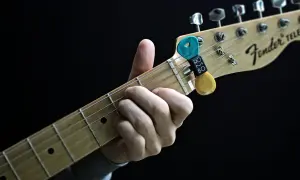 Dłoń grająca akord na gryfie gitary Fender Telecaster z kostkami.