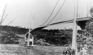 Die Tacoma-Brücke überspannt ein Gewässer, umgeben von bewaldeten Hügeln.
