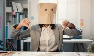 Person med papperspåse på huvudet, med en ledsen min ritad, ger tummen ner. Kanske ett tecken på kontraproduktivt beteende på jobbet.