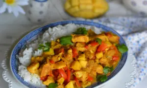Pyszny kurczak z mango po tajsku, podany z ryżem. Aromatyczne kawałki kurczaka, słodkie mango i papryka w złocistym sosie curry.