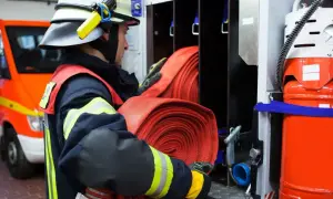 Strażak przygotowuje zwinięte węże tłoczne do akcji.