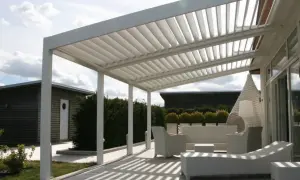 Un moderno porche patio de casa con muebles blancos de mimbre y una pérgola de listones.