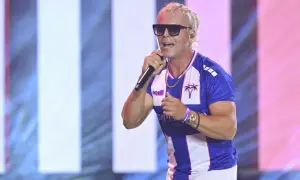 Skolim w niebiesko-białej koszulce śpiewa na scenie, podczas gdy jego **skolim trasa koncertowa** rozgrzewa publiczność.