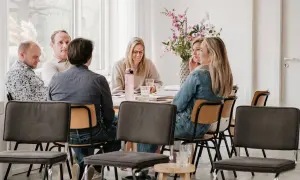 Groep mensen rond een tafel, met een intake formulier coaching op tafel.