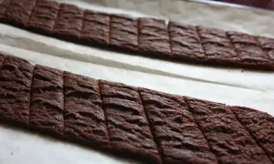 Två rader med sega chokladsnittar på bakplåtspapper, redo att gräddas.