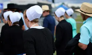 Människor i traditionella kläder, som påminner om amish i Sverige, med vita hättor och hattar.