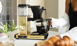 En gyllene Moccamaster brygger kaffe, perfekt för en italiensk frukost med nybakade croissanter.