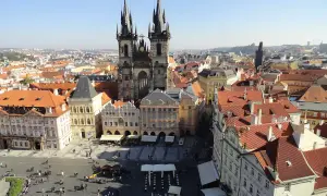 Blick über die Dächer der **Prag Stadt** mit der Teynkirche im Zentrum. Menschen beleben den Platz.
