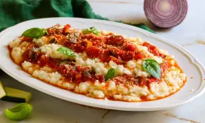 Frascarelli ricetta originale: un piatto cremoso con sugo di pomodoro, verdure e parmigiano, guarnito con basilico fresco.