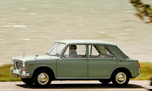 En ljusgrön BMC 1100 kör längs en väg vid vattnet.