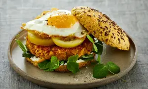 Herzhafter Burger mit einem Spiegelei-Rezept-Topping, Tomatenscheiben, Salat und einer würzigen Pattie auf einem Körnerbrötchen.