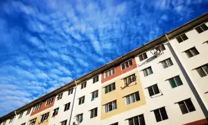 Wielopiętrowy budynek mieszkalny, typowe mieszkanie socjalne, pod błękitnym, pofalowanym niebem.