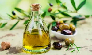 Olio di sansa in bottiglia di vetro, con olive miste e rametto di rosmarino. Un condimento versatile, l'olio di sansa è commestibile e perfetto per ogni piatto.