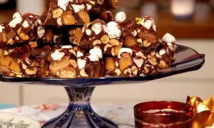 En hög med chokladbitar med nötter, karamell och marshmallows. En härlig rocky road-frestelse på ett blått fat.